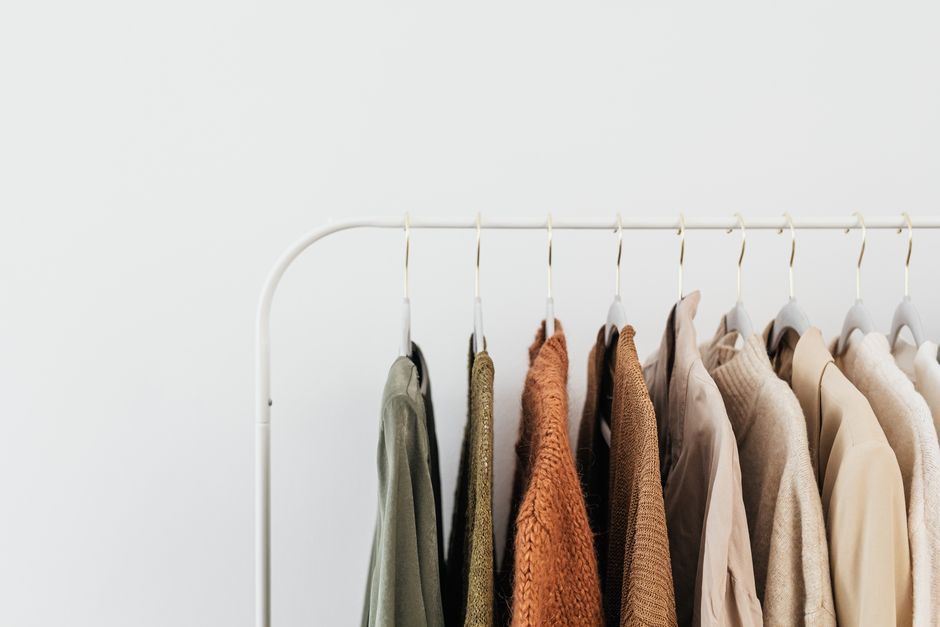 A minimalist clothing rack displaying neutral-toned outfits in an organized indoor setting.